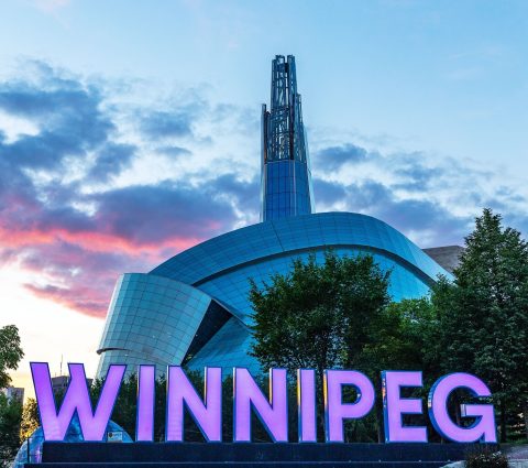 Winnipeg sign in front of  the Canadian Museum for Human Rights at sunset