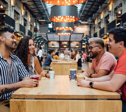 Four people enjoying drinks while seated at a table at the Common at The Forks